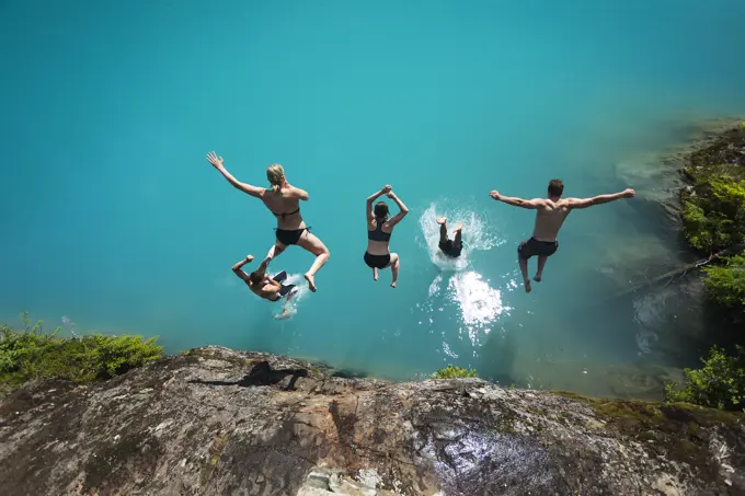 Five friends dive into the turquoise waters of Century Sam lake in Strathcona Park, Vancouver Island, British Columbia, Canada