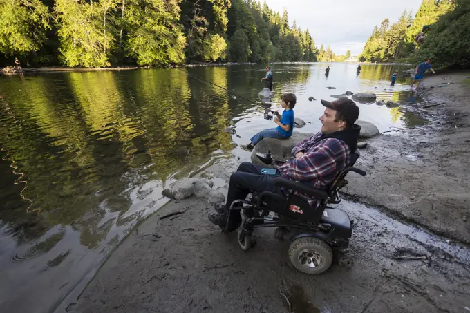 A disabled father and his son fish along the shores of the Campbell River, Vancouver Island