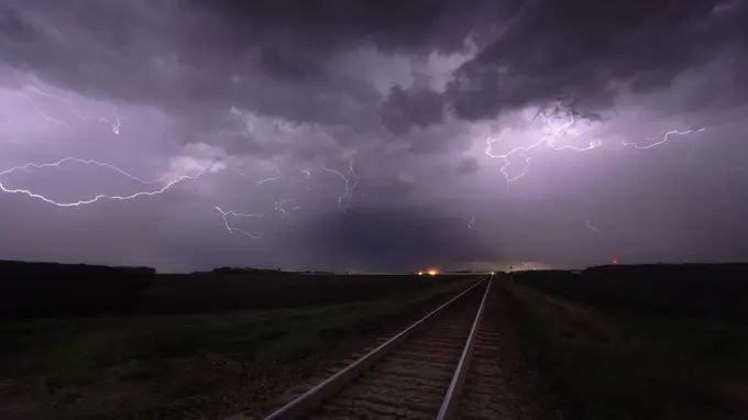 Storm with lightning flashing overhead railway crossing and train tracks in southern Manitoba, Canada