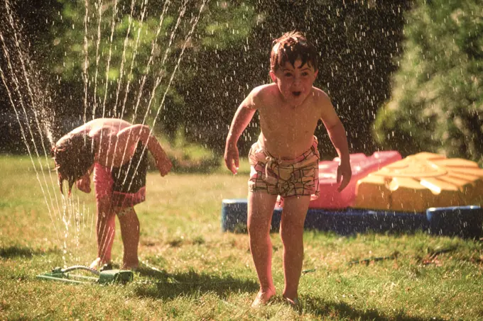 Boys play in sprinkler