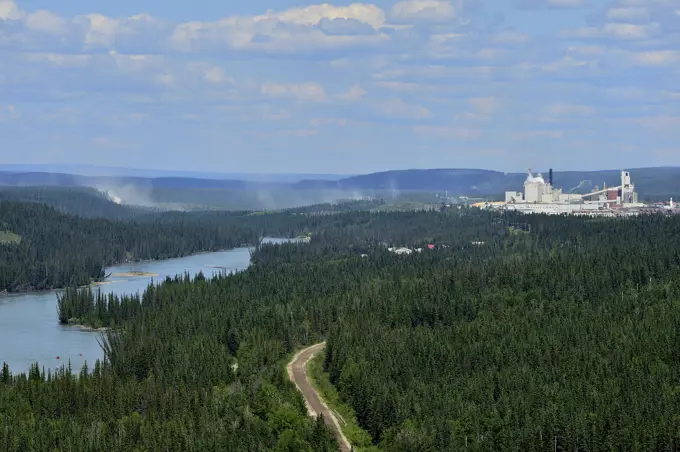A landscape image of the Athabasca river looking east with dust from the logging roads and pulp mill in the background at Hinton, Alberta, Canada