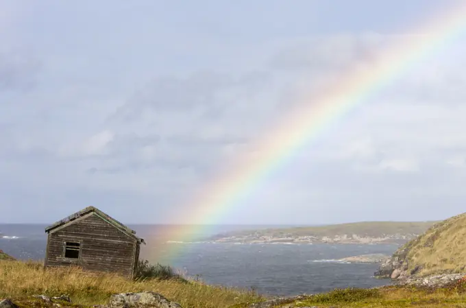 Rainbow over abandoned building at resettled outport, Great Caribou Island, Labrador, Canada