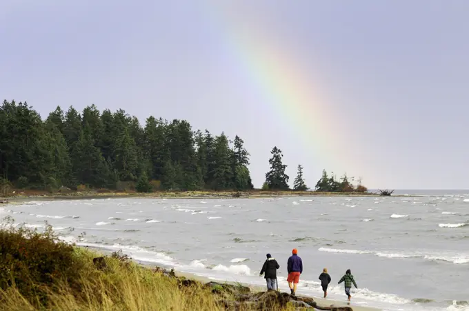 A family enjoys a walk along the beach in Parksville, British Columbia, Canada.