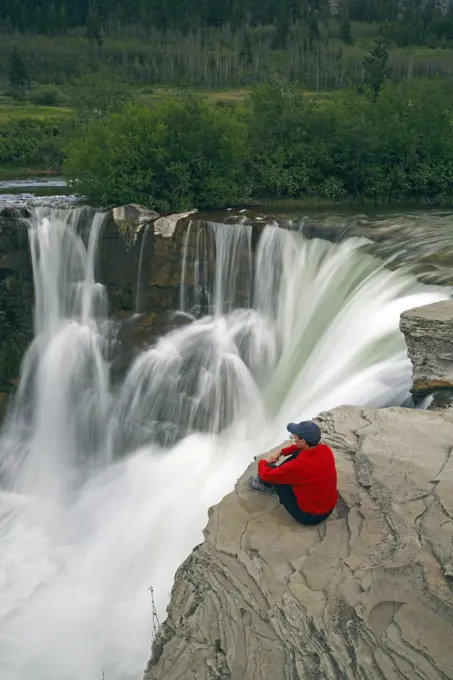 Man sitting next to Lundbreck Falls, Alberta, Canada
