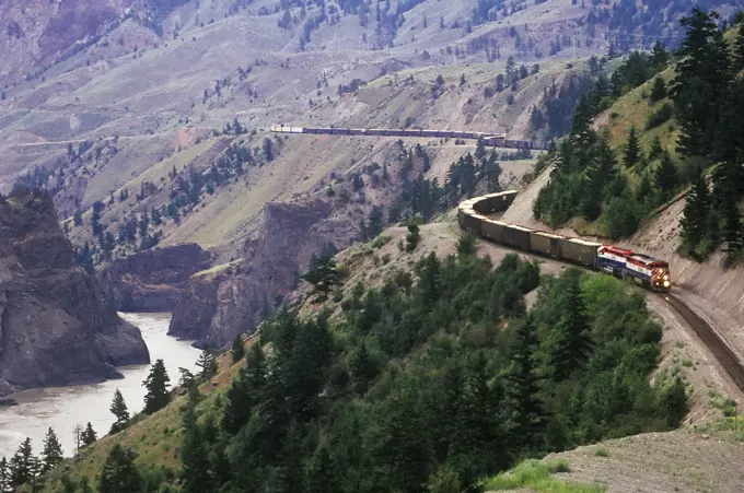 BC Rail freight train travels through central BC above the Fraser River, British Columbia, Canada.