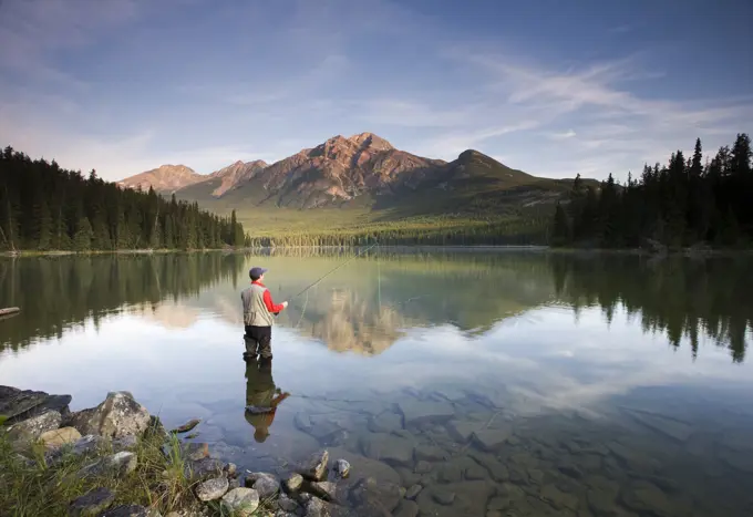 Middle aged male fly fishing in Pyramid Lake, Jasper National Park, Alberta, Canada