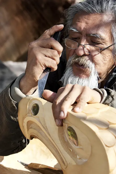 A First Nations carver works on an Eagle piece, carved from yellow cedar, Tofino, Vancouver Island, British Columbia, Canada