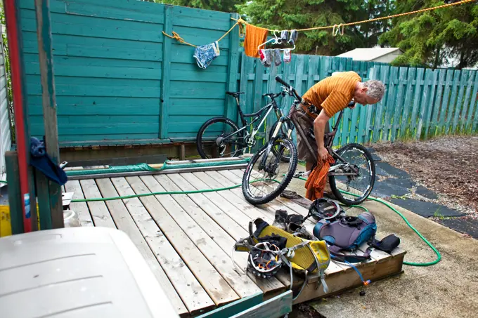A middle aged man washing down his mountain bike after a muddy ride in Golden, BC