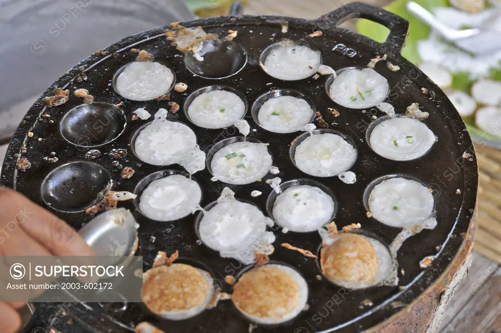 Coconut Pudding (Kanom Krok in Thai) being cooked over traditional charcoal burner