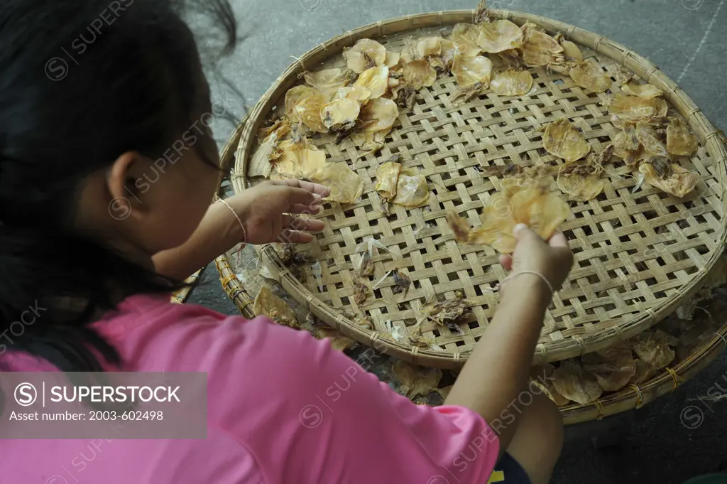 Thailand, Chon Buri, Ban Saen, Nongmun Market, Woman sorting dried squid on tray