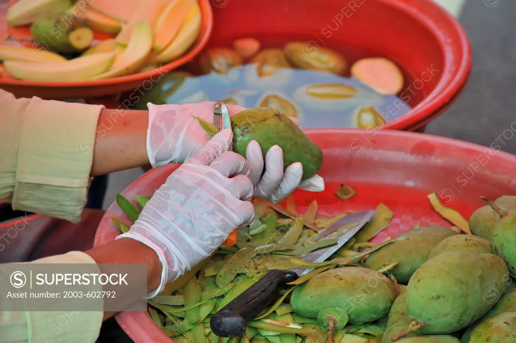 Thailand, Khon kaen, Woman prepares Green Mangoes for fresh fruit snacks and to shread for mango som tom (Thai spicy coleslaw type salad)
