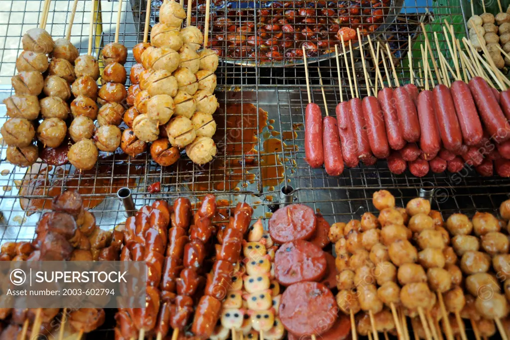 Thailand, Khon kaen, Thai Pork satays and sausage snacks with sweet sauce at vendors stall