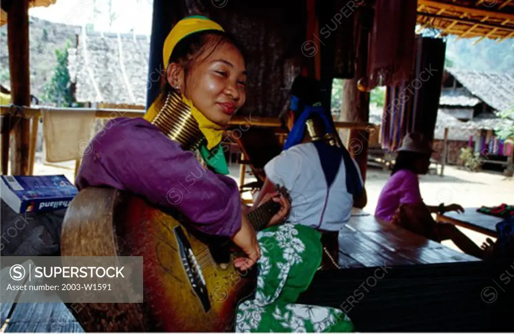Side profile of a Padaung woman playing a guitar, Ban Huay Pu Keng, Thailand