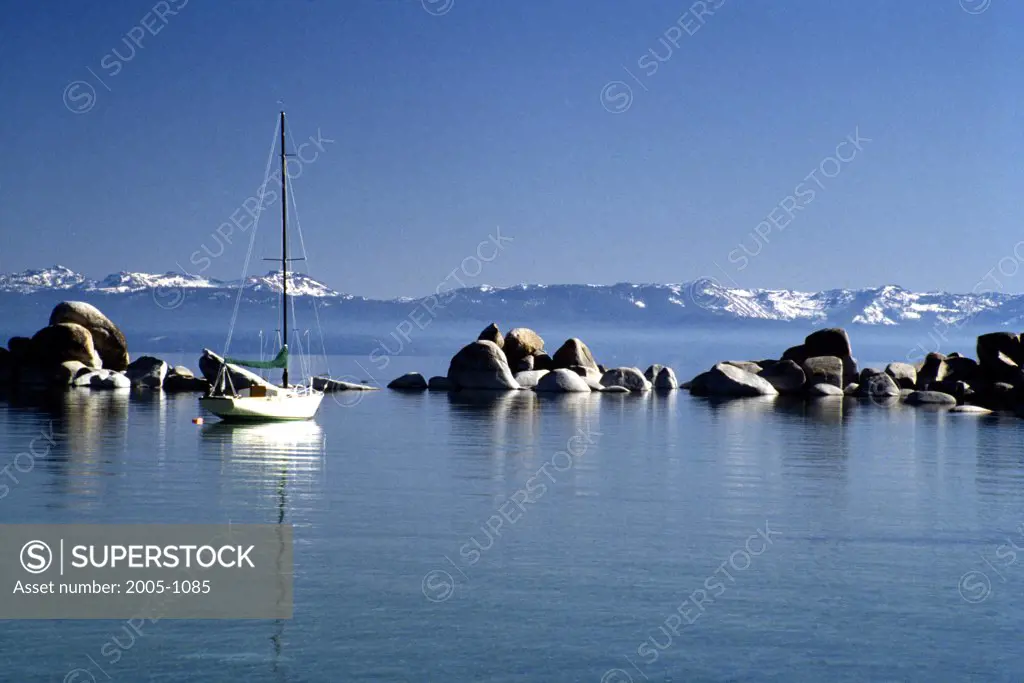 Sailboat in a lake with snowcapped mountains in the background