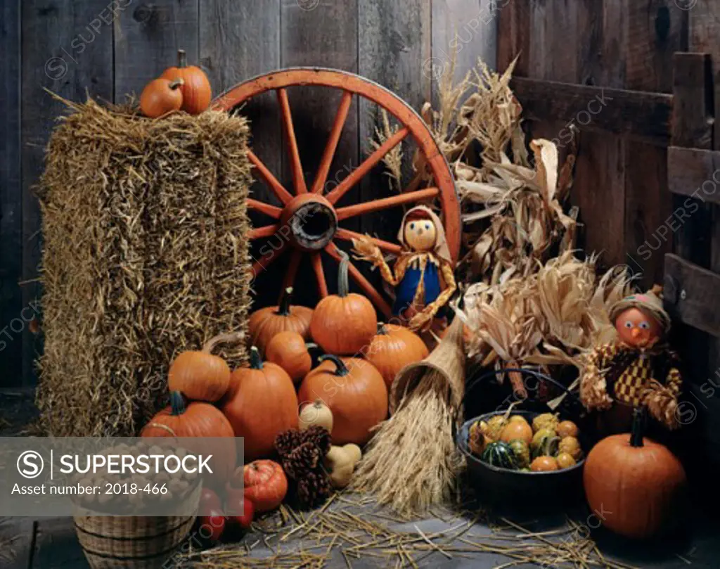 Assorted vegetables next to a hay bale and a wagon wheel
