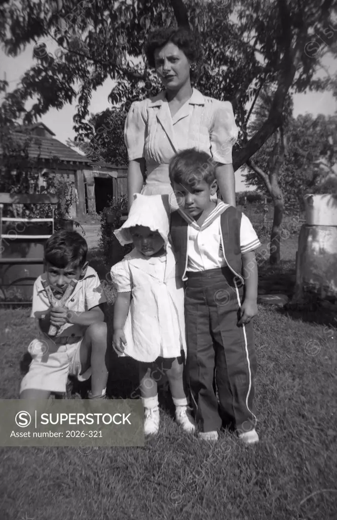 Mid adult woman with her three children standing in a lawn
