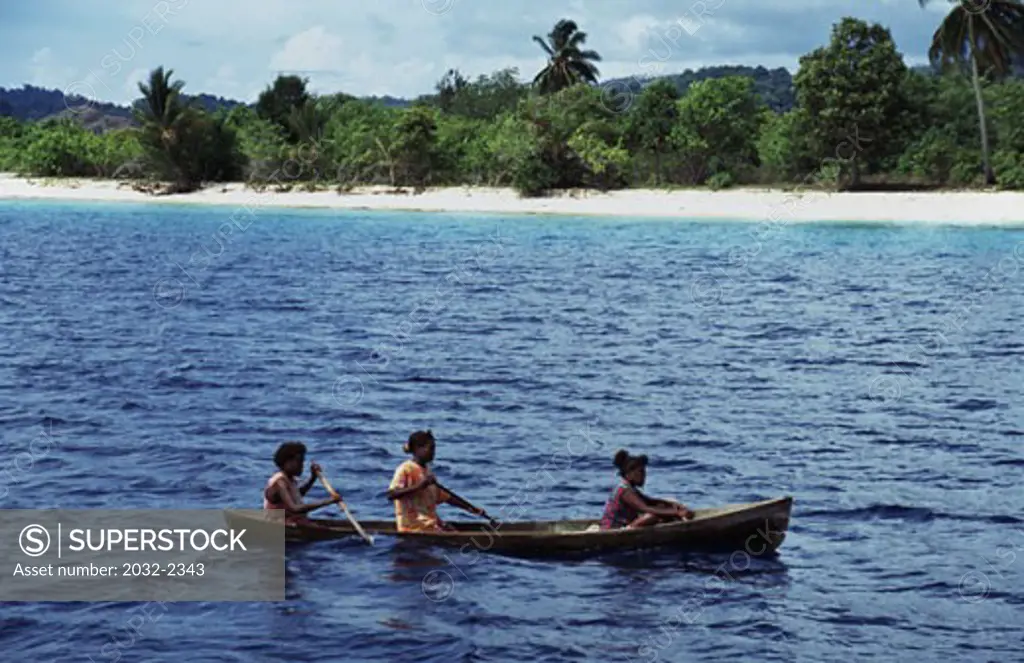 Three people rowing a boat in the ocean, Solomon Islands