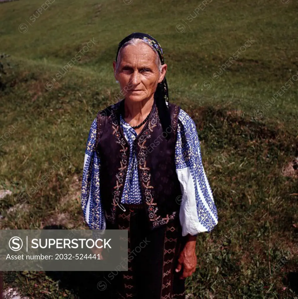 Romania, portrait of peasant woman standing in field