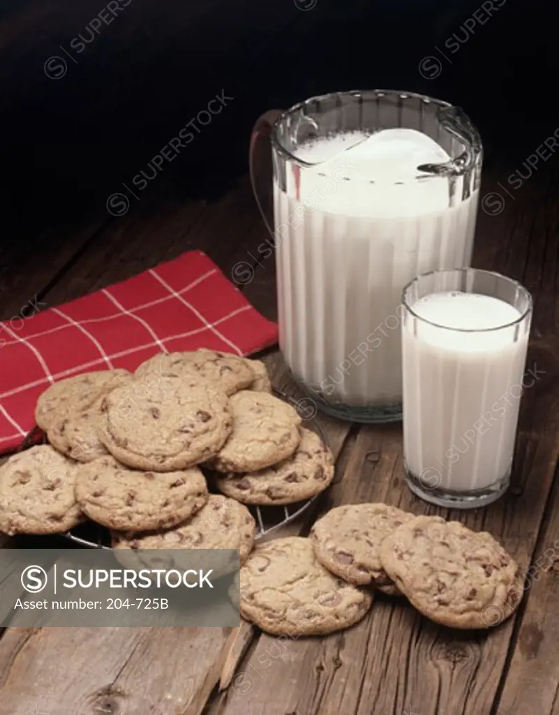 Close-up of chocolate chip cookies with milk in a glass and a pitcher