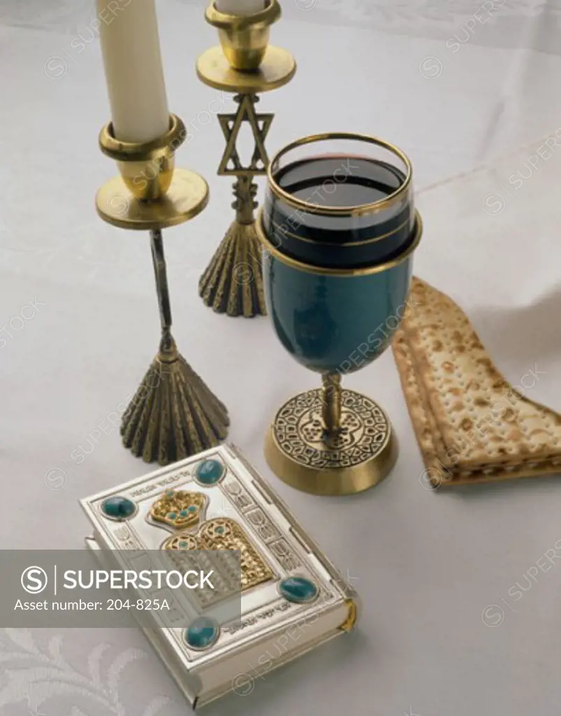 Close-up of two candlestick holders with a glass and a matzo cracker