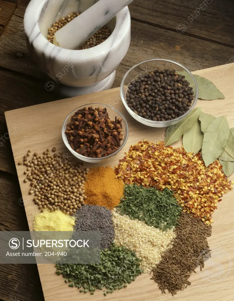 High angle view of spices on a cutting board with a mortar and pestle