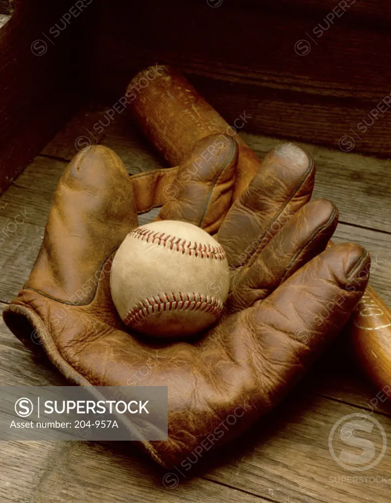 Close-up of a baseball glove with a baseball bat and a baseball