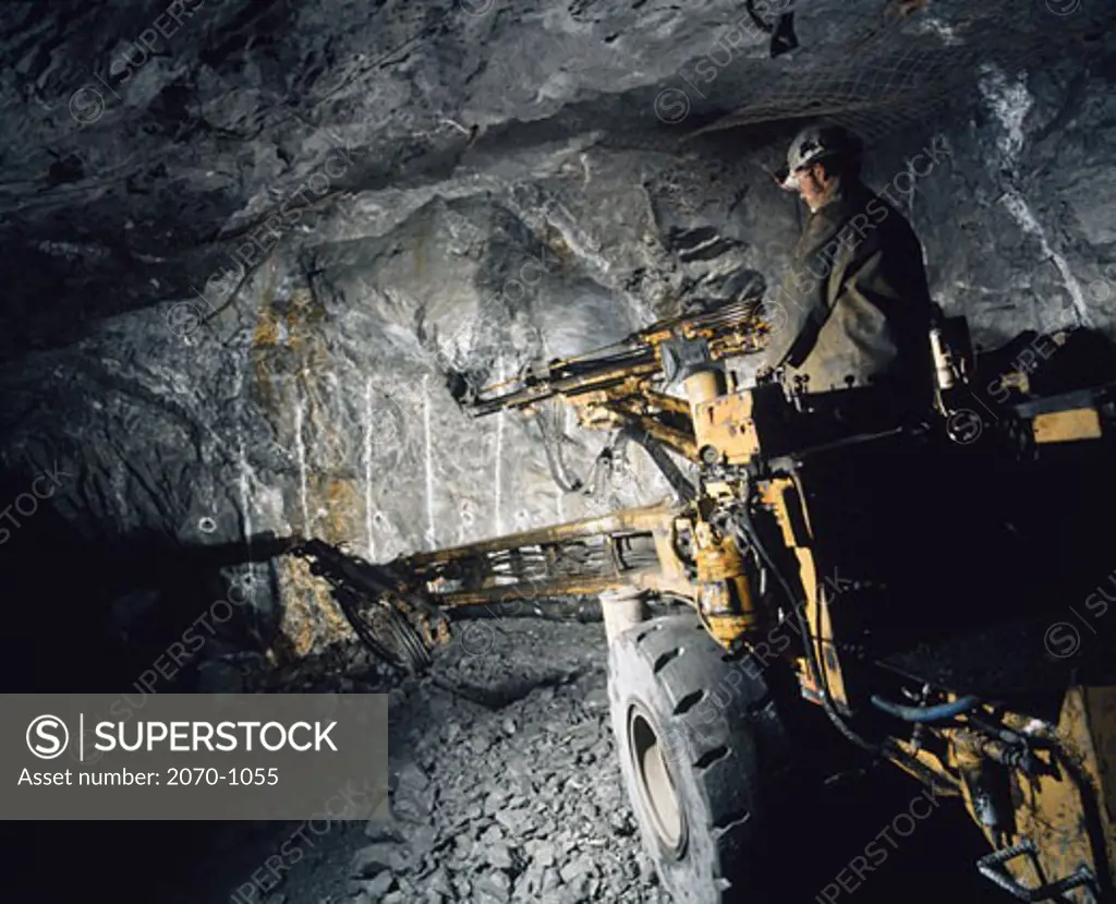 Miner working with twin boom drill in a mine, Faro, Yukon, Canada