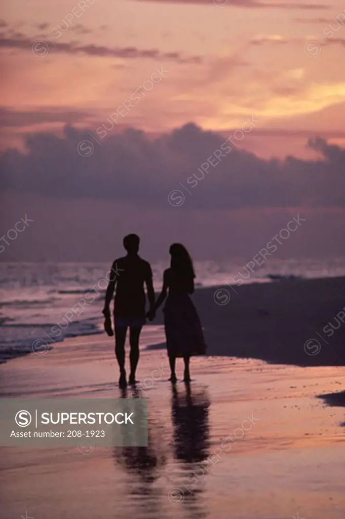 Silhouette of a young couple strolling on the beach