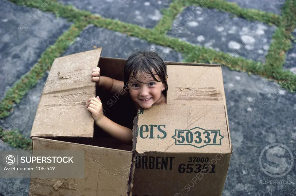 High angle view of a girl sitting in a cardboard box