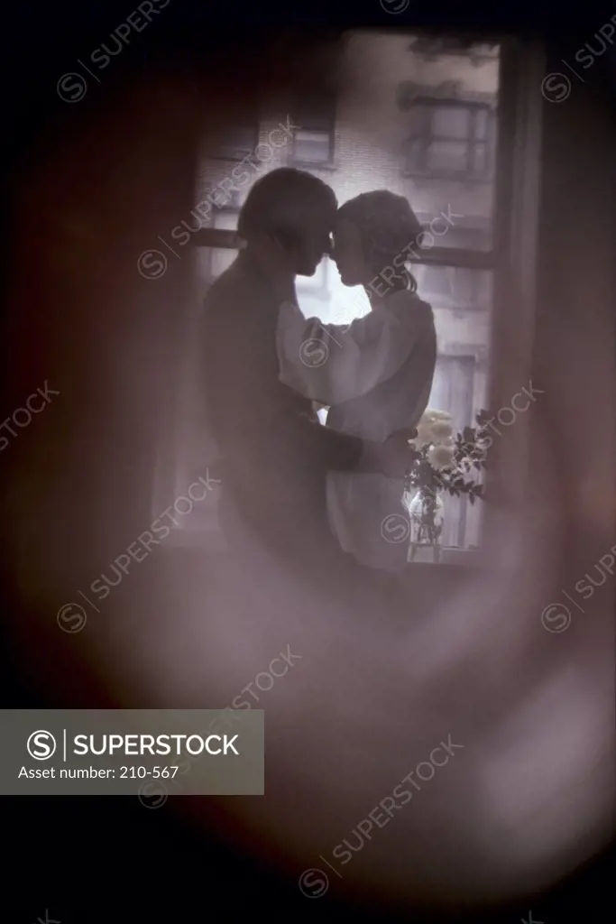 Young couple romancing in the room viewed from a keyhole