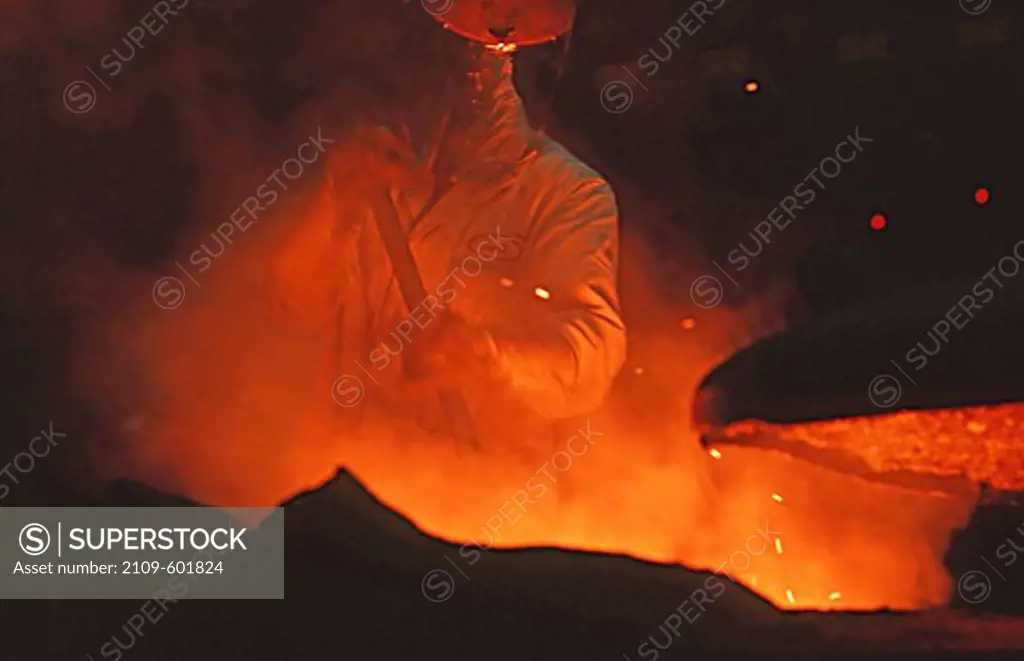 Foundry worker stirring a molten mix of titanium alloy