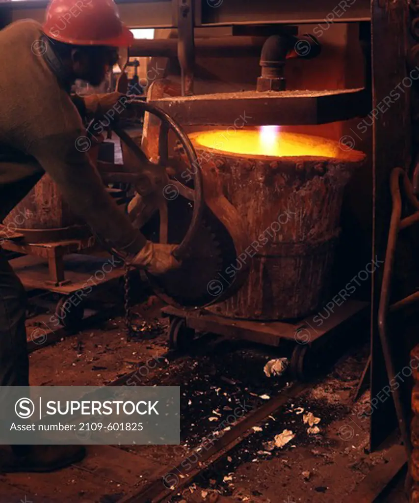 Foundry worker heating a foundry smelter pot