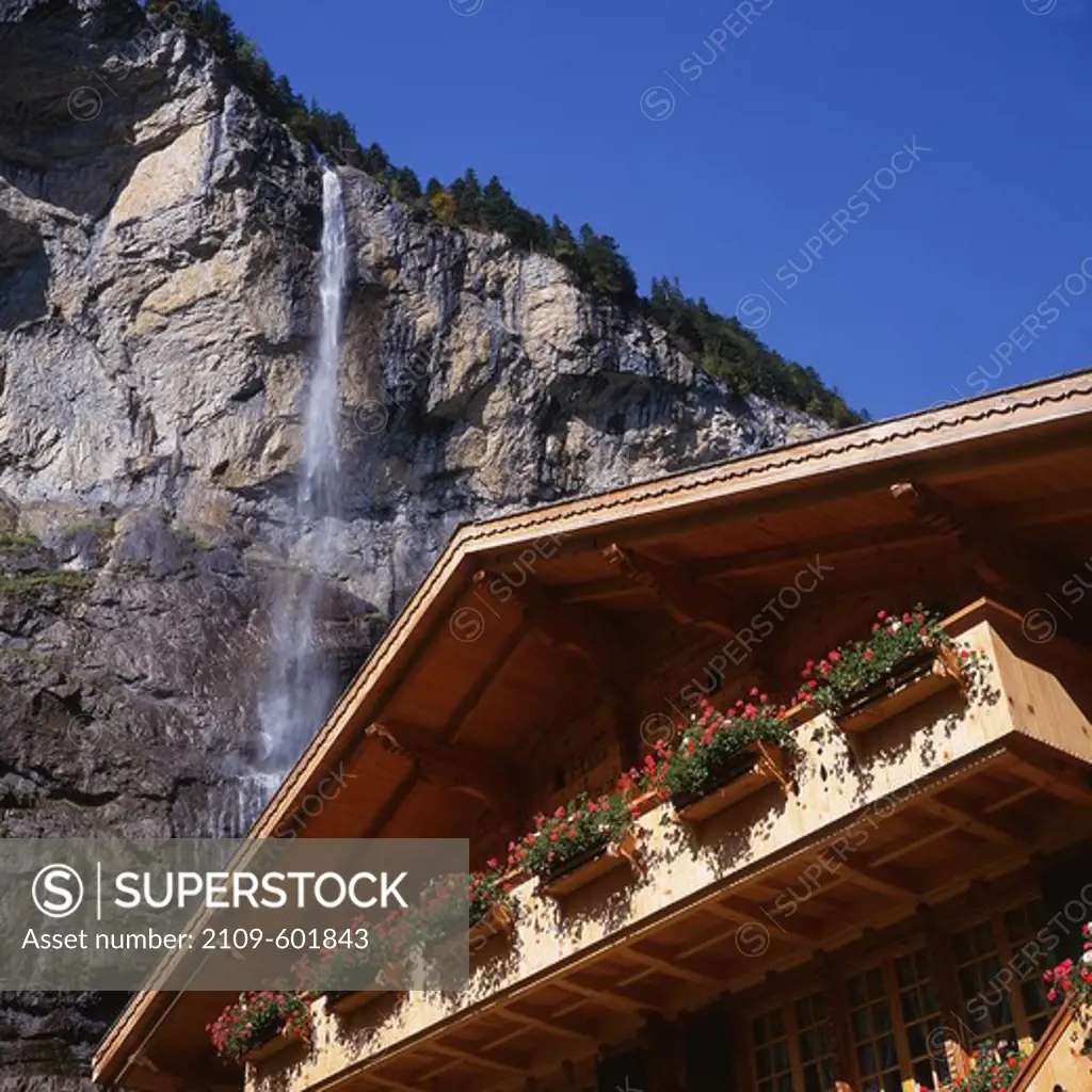 Low angle view of window boxes at a traditional Swiss house with Staubbach Falls in the background, Lauterbrunnen, Berner Oberland, Switzerland