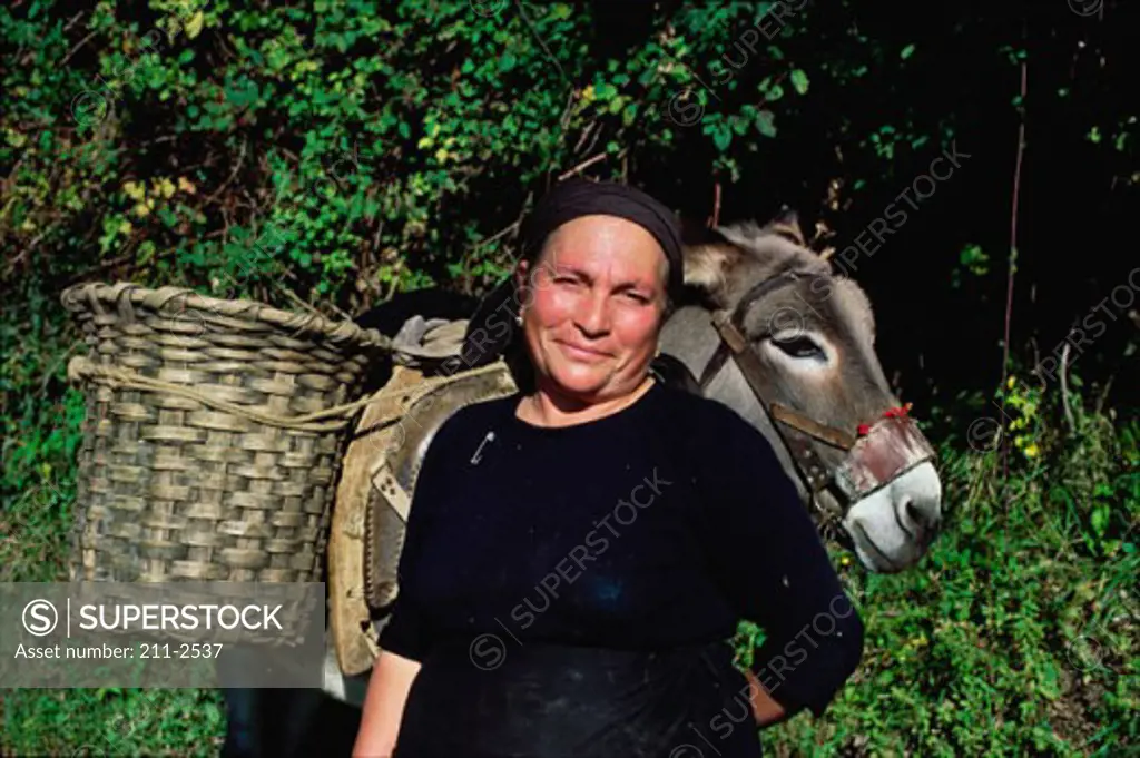Portrait of an elderly woman standing with a donkey in Italy