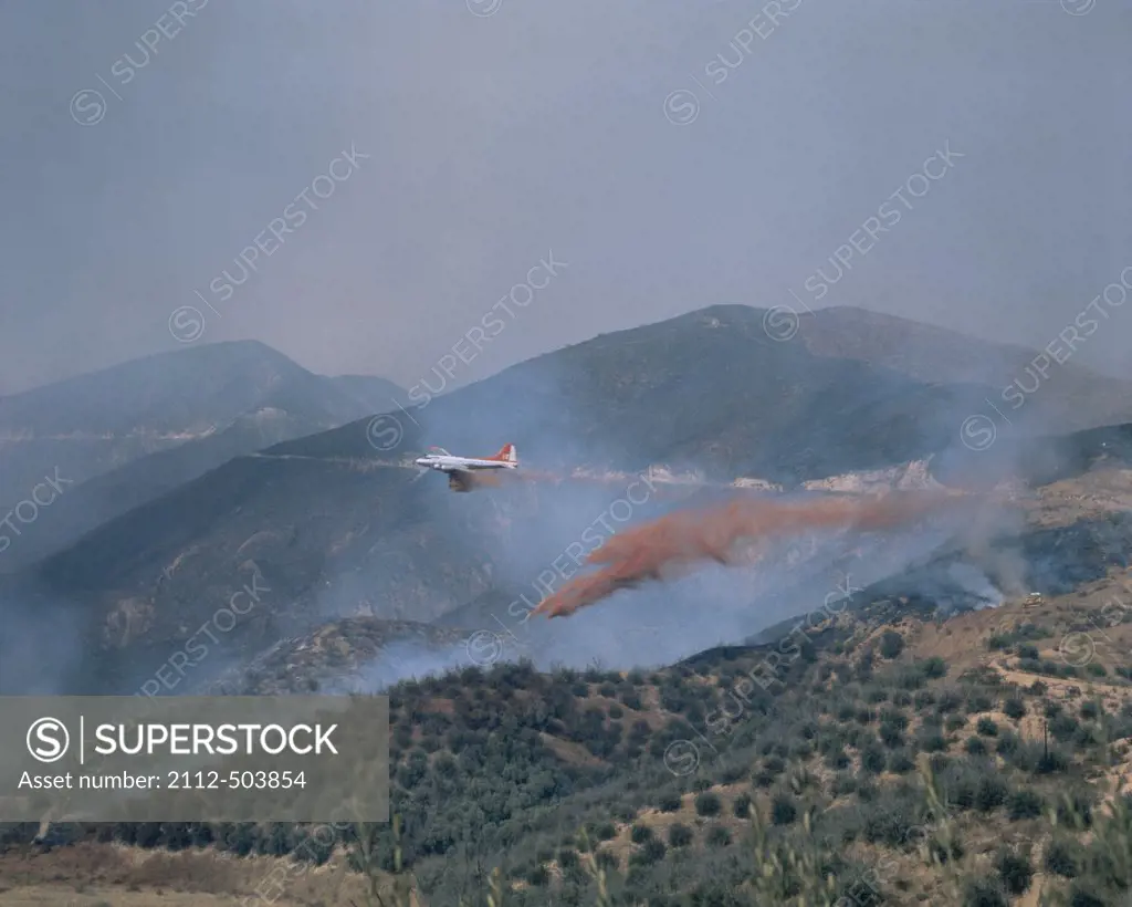 A plane extinguishing a forest fire by dropping chemicals