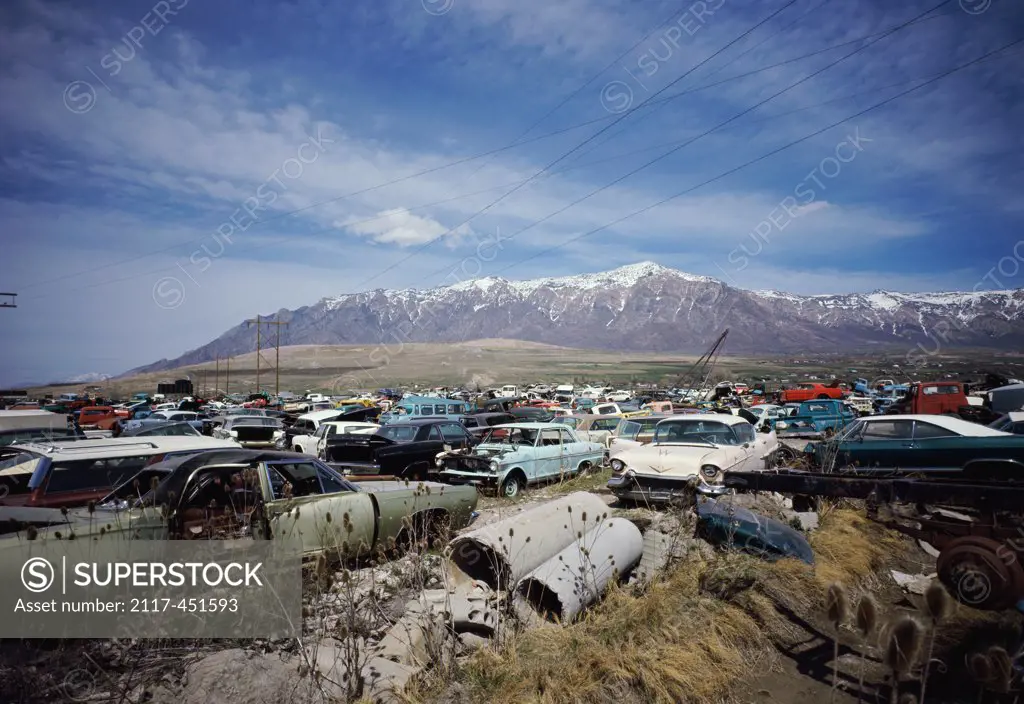 Junkyard with snow covered mountains in the background, Ogden, Utah, USA