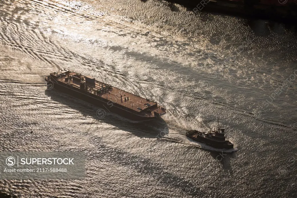 USA, New York City, Aerial view of tug pulling barge down East River