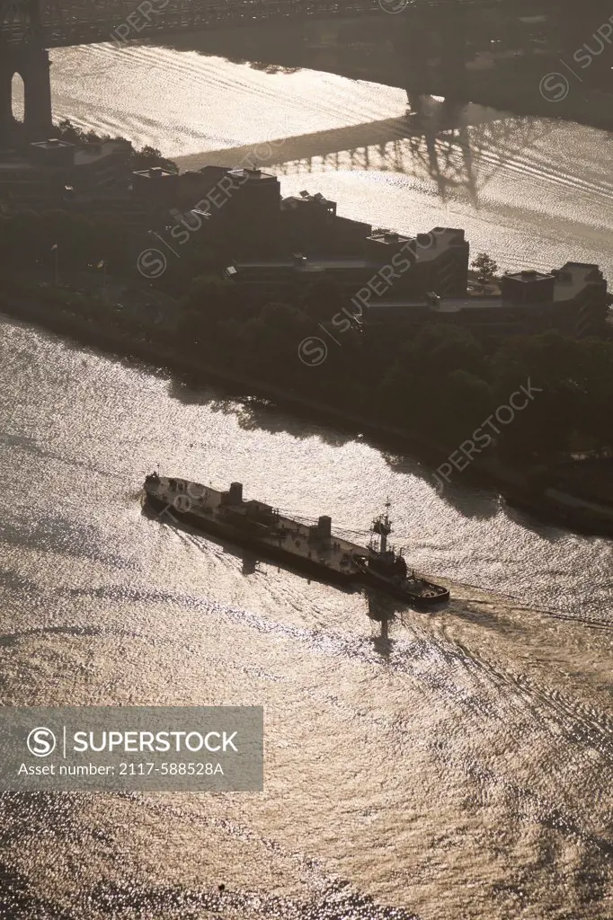 USA, New York City, Aerial view of tugboat pushing barge up East River
