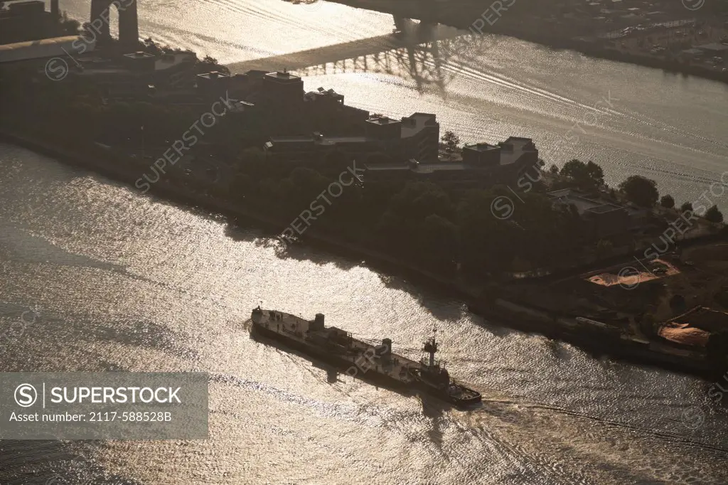 USA, New York City, Aerial view of tugboat pushing barge up East River