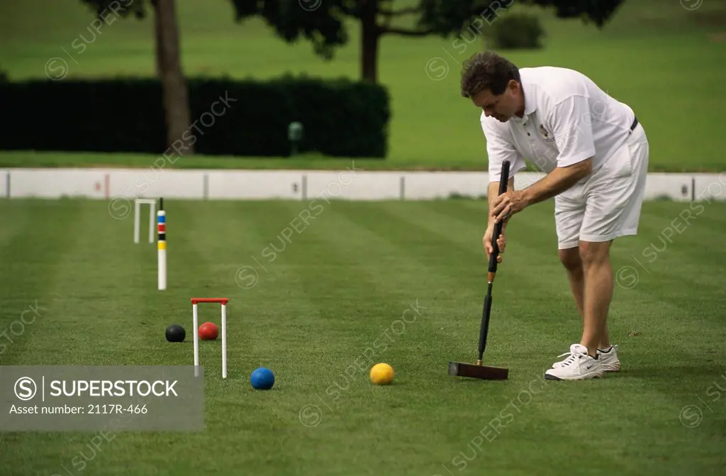 Side profile of a mid adult man playing croquet