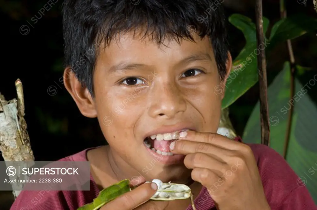 Portrait of a boy eating Shimbillo fruit, Yarina, Loreto Region, Peru