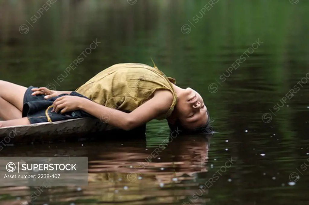 Boy lying in a dugout canoe, Rio Yanayacu, Yarina, Loreto Region, Peru