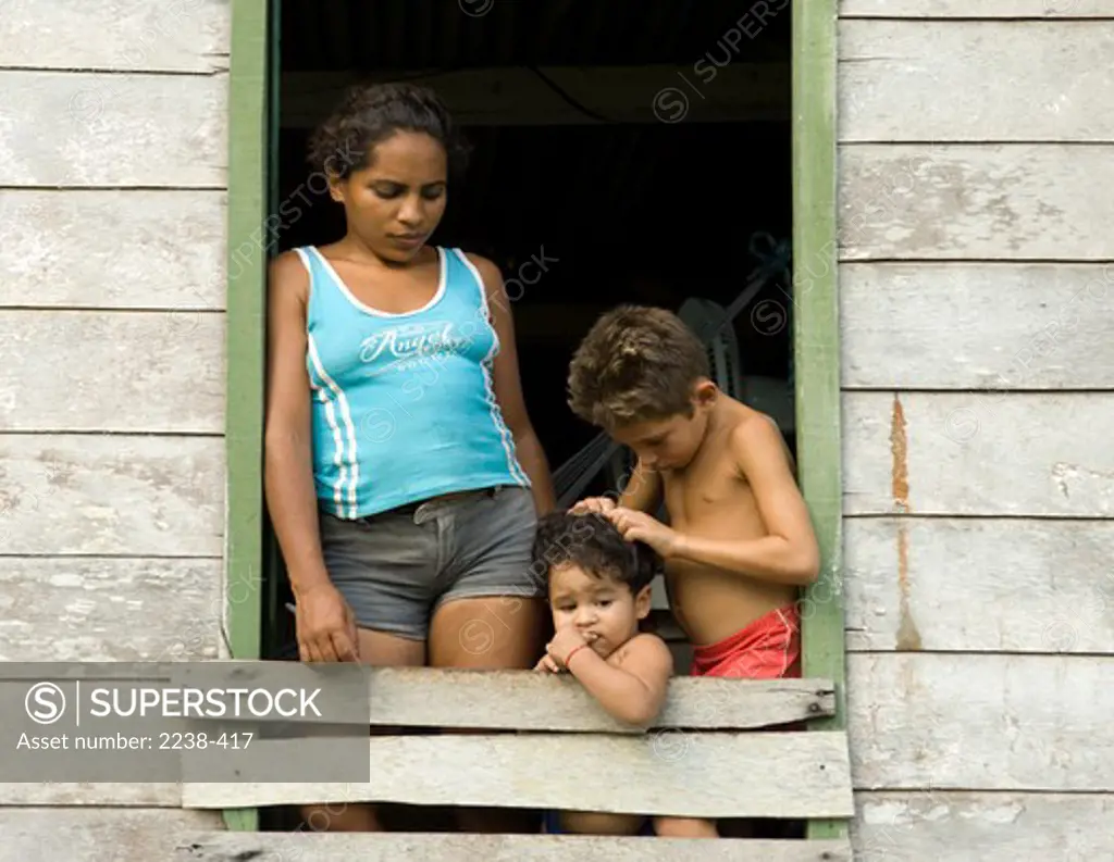 Boy examining his sister for head lice, Iranduba, Rio Solimoes, Amazonas, Brazil