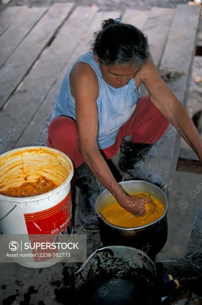 Mature woman fermented peach palm fruit pulp with water to make beer, Peru