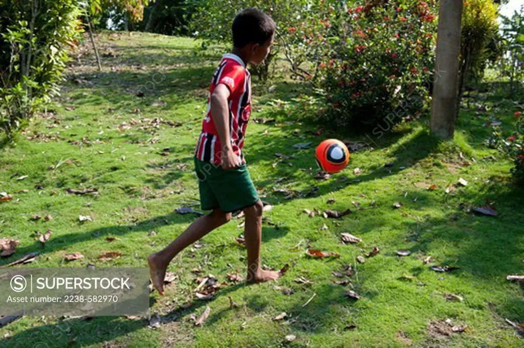 Franco, 10 yrs, kicking soccer ball in his front yard. Dona Claudia's home. Vila Valente, lower Tefe River, a few km downstream from Tefe, Amazonas, Brazil, 8-30-12