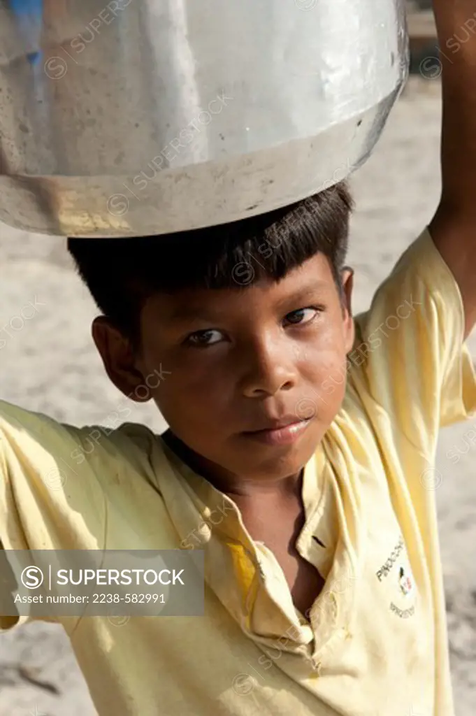 Boy carrying water in a metal pot. Sao Francisco do Paxiubinha, Tefe River, Amazonas, Brazil, 9-9-12