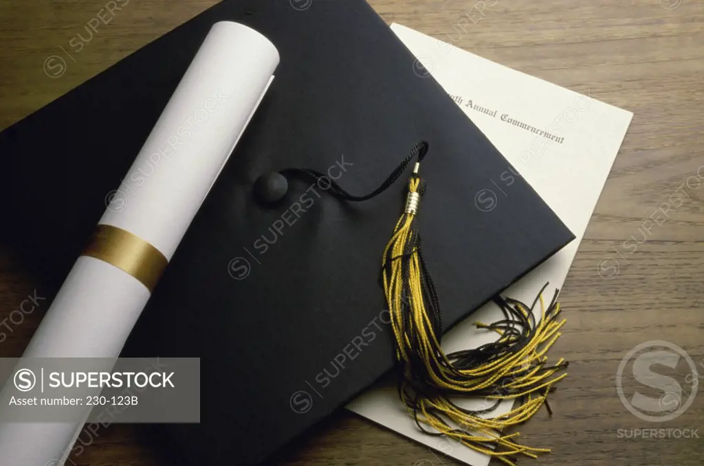 Close-up of a certificate with a mortar board and a diploma on a table