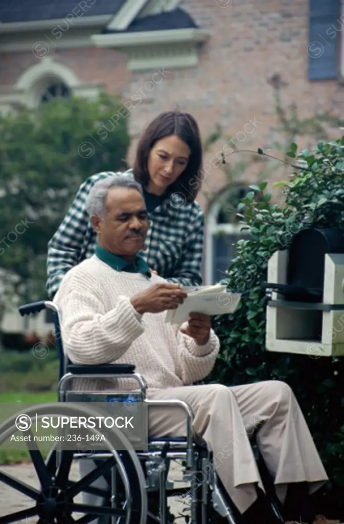 Mid adult couple near a mailbox looking at mail