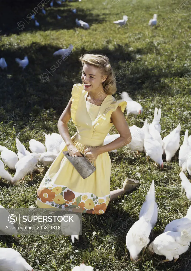 High angle view of a teenage girl feeding chickens in a field