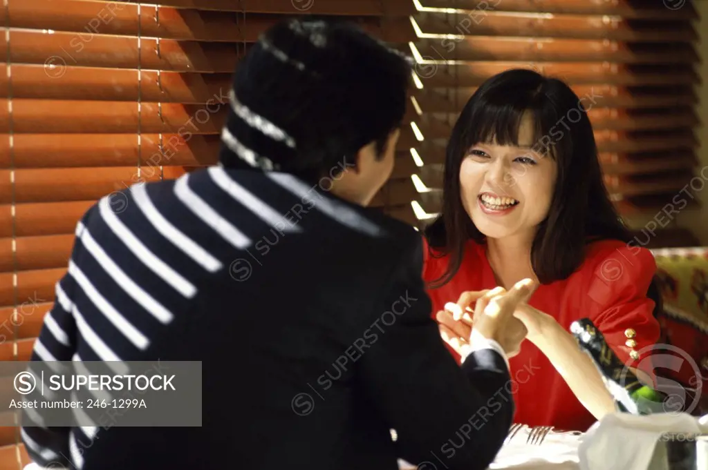 Rear view of a young man holding a young woman's hand in a restaurant